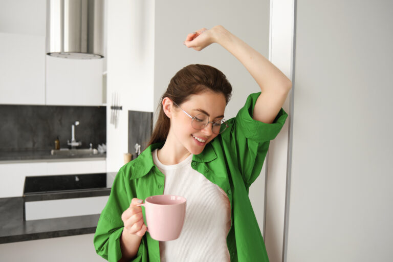 Portrait of carefree, beautiful young woman, relaxing at home, drinking cup of coffee